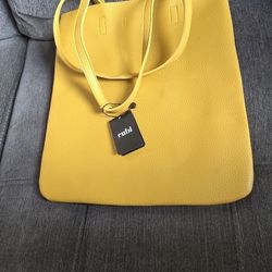 Vibrant yellow tote bag from Rubi. This bag has a pebbled faux leather texture and features a magnetic snap closure. It is equipped with two long shou
