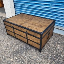 Industrial trunk style coffee table. Top slides open for storage. Measures approx: 42" wide x 26" deep 