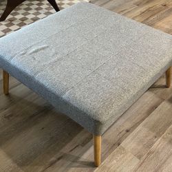Square grey ottoman/coffee table with wood legs   