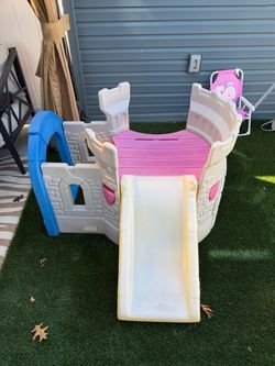 Little Tikes Climb and Slide Castle play set featuring gray and white walls, a pink platform, a built-in slide, and a blue archway entrance.