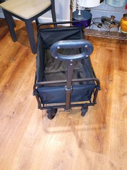 Black collapsible utility wagon with handle and wheels.