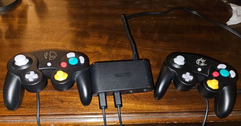 Two Super Smash Bros. Edition GameCube Controllers and an official Nintendo GameCube Controller Adapter.