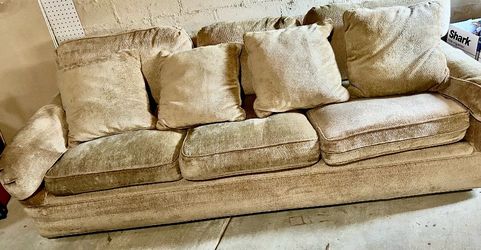 Long custom made tan fabric couch with matching zip up pillows