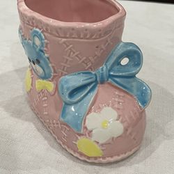 Vintage pink ceramic baby bootie planter with blue bow and floral accents.