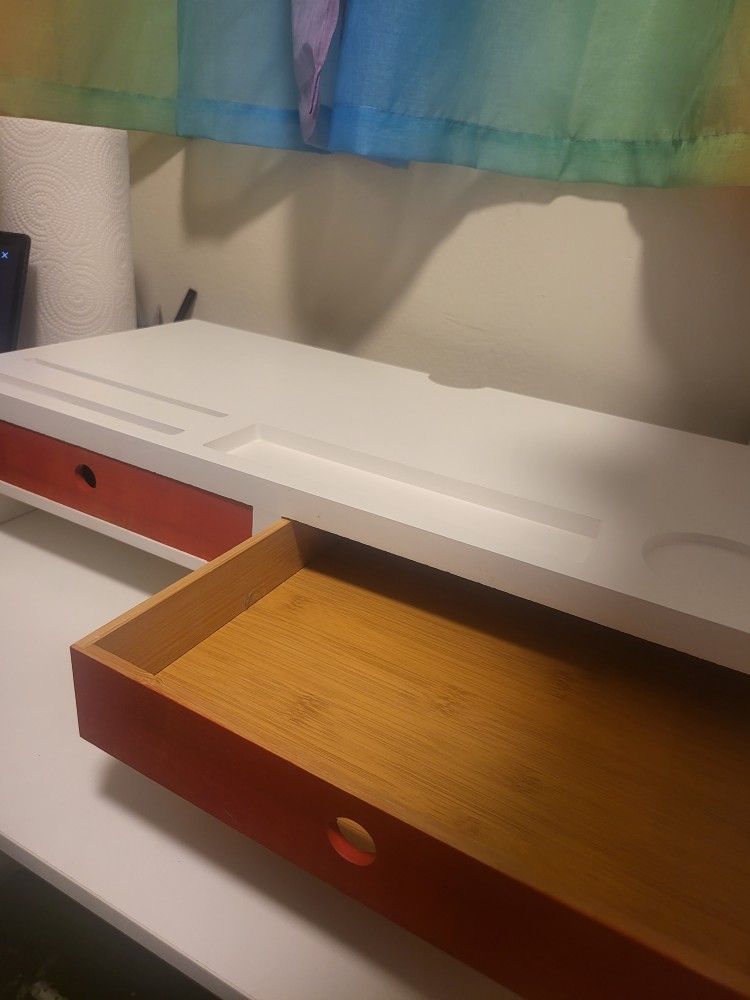 White monitor stand/riser with 2 orange drawers and storage cutouts