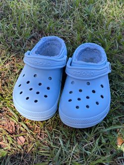 Fleece-lined light blue Crocs Classic Clogs. These shoes are size Men's 4 / Women's 6. They have a synthetic upper with a fuzzy interior lining and a
