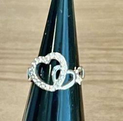 Elegant silver-tone ring featuring two interlocking hearts. Sparkling textured design adds subtle shine. Comfortable band for everyday wear. A romanti