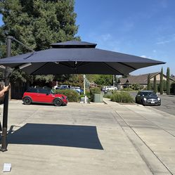 NEW BLUU 10FT 2 TIER SQUARE CANTILEVER UMBRELLA IN NAVY BLUE, 360 ROTATION, HAS LAG BOLTS TO MOUNT TO GROUND..DOES NOT HAVE A BASE 