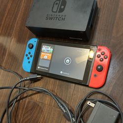 Nintendo Switch with red and blue joycons dock and cords