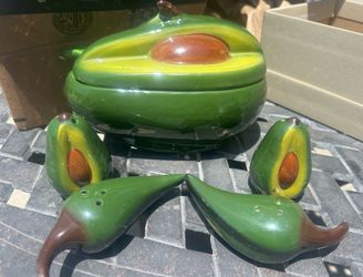 glossed ceramic, avocado-shaped lidded bowl for serving guacamole, accompanied by matching avocado or chili pepper-shaped salt and pepper shakers.