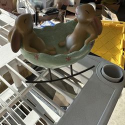 This is a vintage-style resin figurine of laughing bunny rabbits rocking in an Easter egg cradle