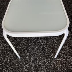 LIKE NEW WAS NEVER OUTSIDE This is a white metal and glass outdoor side table.