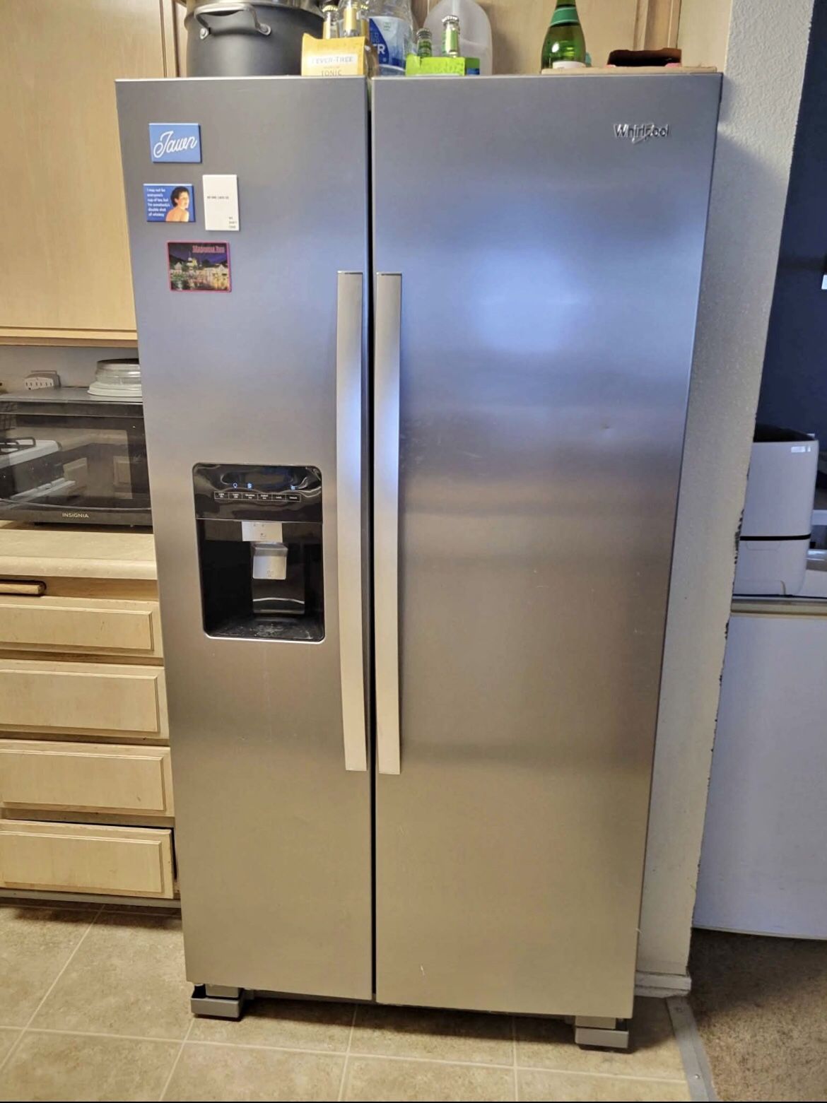 Whirlpool side-by-side fridge and freezer with water dispenser and ice maker.
