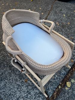 woven baby bassinet / Moses basket on a folding wooden stand.