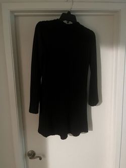 New Black ribbed knit dress. This long-sleeved garment has a mini length and a crew neckline. The fabric is a vertical ribbed texture throughout