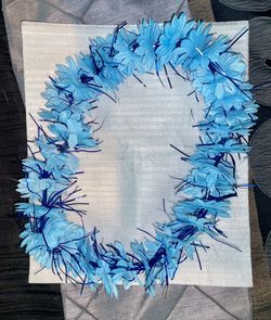 Light Blue Flowered Lei With Royal Blue Tinsel Inserts Between Flowers