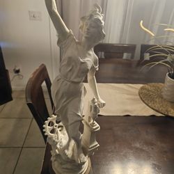 sculpture depicts a female figure in a flowing gown, often