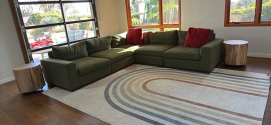 Large green couch, pillows, rug, and end tables