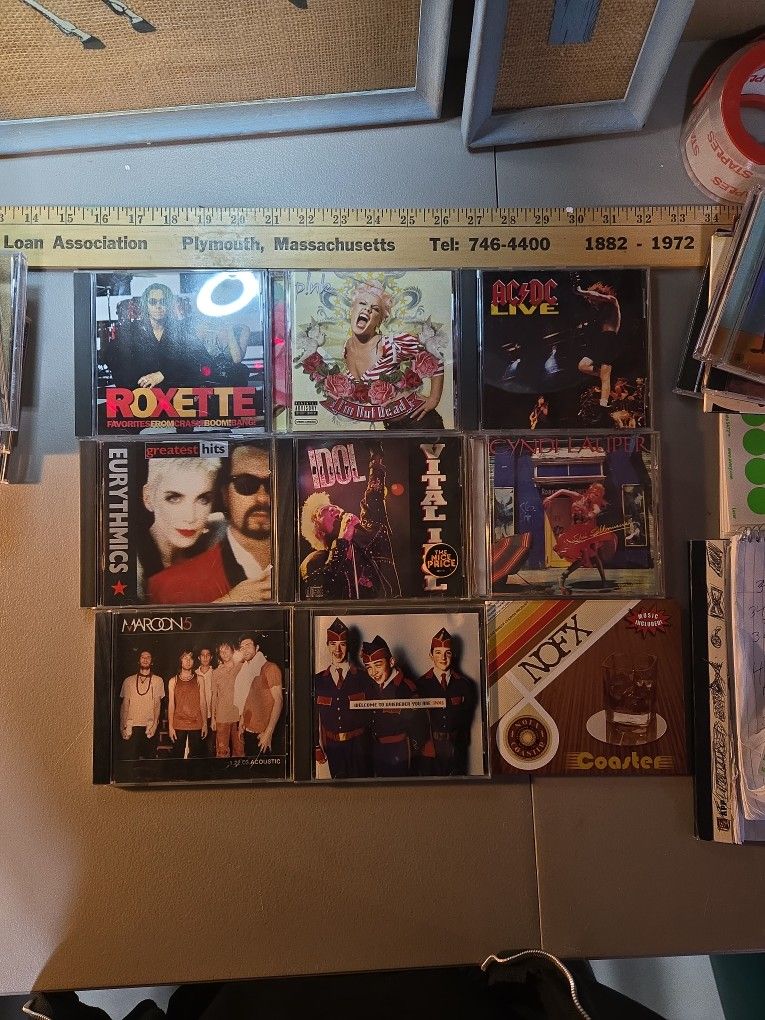 Collection of nine CDs, including albums by Roxette, Pink, AC/DC, Cyndi Lauper, Billy Idol, INXS, Maroon 5, and NOFX.