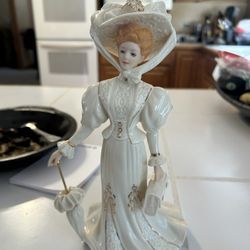Lenox "Grand Voyage" Victorian lady figurine.  It is made of fine porcelain.  The figurine is hand-painted and accented with 24-karat gold.  It was pa