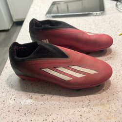 laceless Adidas X Speedportal+ FG soccer cleats in a black, white, and solar red/pink colorway.