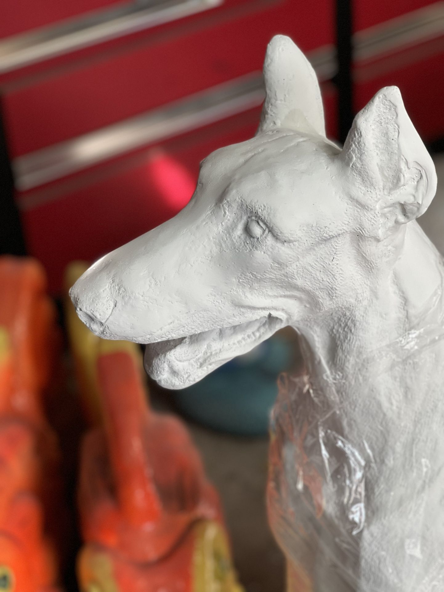 Solid Doverman pincher concrete statue has been primed and lower base has been colored green for grass