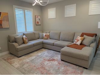 Beige L-shape Sectional with throw pillows and blanket
