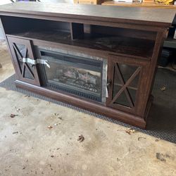 Dark brown fireplace TV stand with remote.