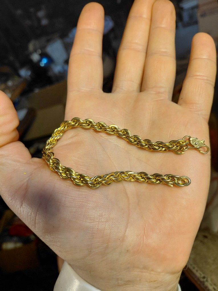  is a gold-toned rope chain bracelet with a lobster clasp. 