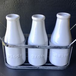 Trio of Porcelain Milk Bottle Vases w/Raised Saying: Bloom,Grow, Thrive On each Bottle. All Displayed in  a Wire Rack.
