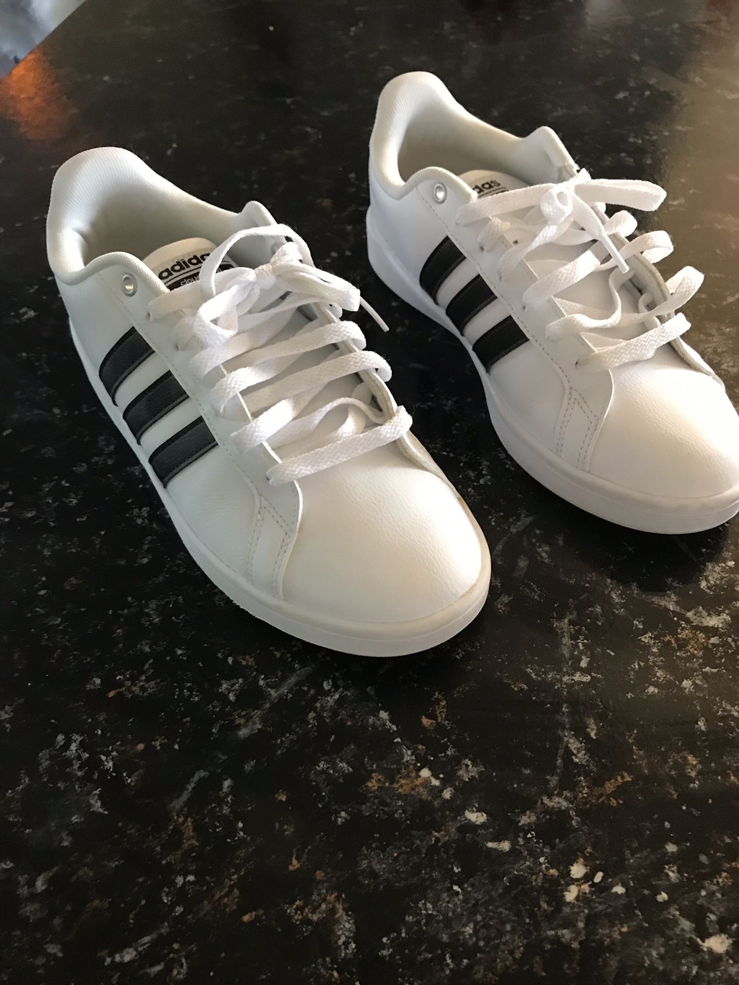Adidas size 8 men’s white and black striped logo shoes.
