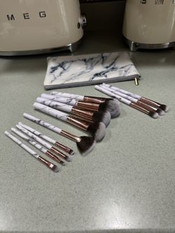 makeup brush set with white marble-look handles, rose gold ferrules, and a matching travel pouch. 