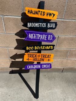 The image shows a handmade wooden Halloween directional yard sign