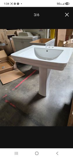 White ceramic pedestal sink. Has a basin with three faucet holes and one drain hole