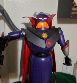 Interactive Emperor Zurg Action Figure is made of Purple and Black Plastic w/ a Red Cape. This Disney Pixar model has light-up eyes and mouth activate
