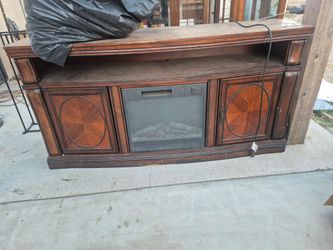 dark cherry wood finish entertainment center with a built-in electric fireplace insert and side cabinets.