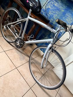 This is a silver Specialized Sirrus hybrid fitness bicycle featuring an aluminum frame and a triple crankset.