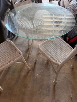 White wicker table with three chairs and glass top