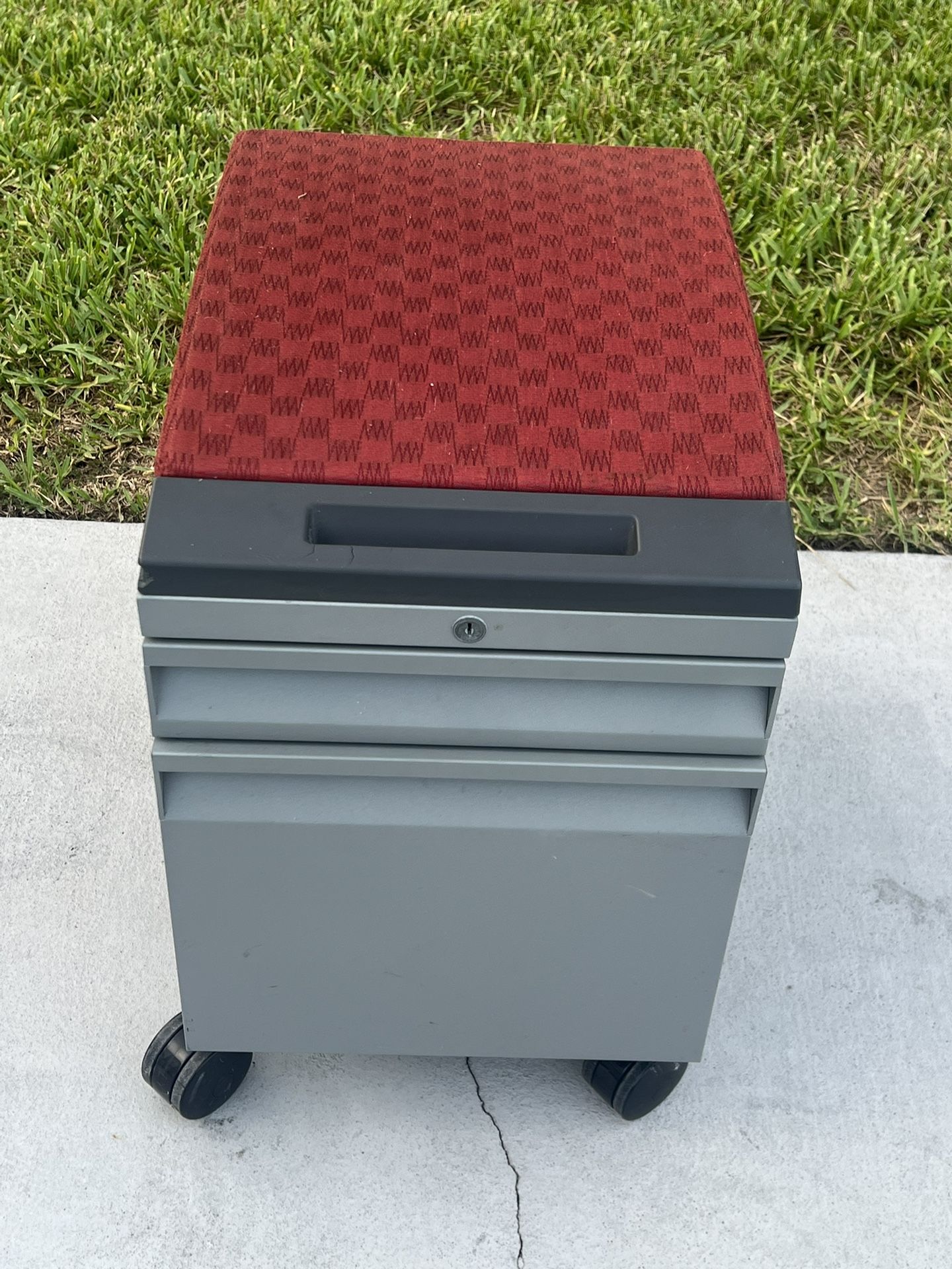 MOBILE PEDESTAL WITH RED CUSHION . Used in good condition the cushion is distressed in a few areas. No key. Can be rekeyed or add a lock on the side.