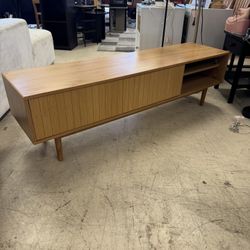 light oak mid-century modern style media console featuring a fluted tambor sliding door and open shelving on the right side