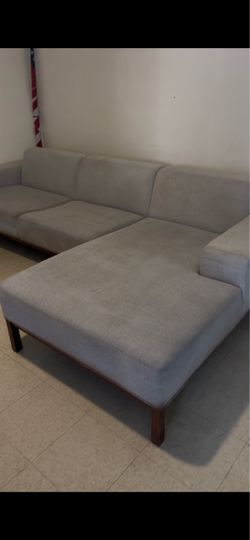 Modern sectional sofa has light gray fabric upholstery and a dark wood frame base. The piece includes a right-arm-facing chaise and two seat cushions.