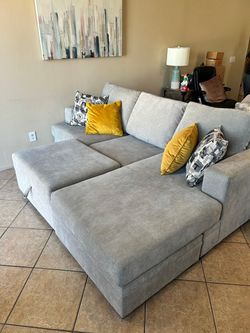 DELIVERY AVAILABLE 🚛. Gorgeous Light grey sectional couch with reversible chaise and storage ottoman LIKE NEW!