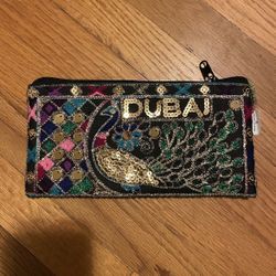 Colorful clutch with peacock design and Dubai text.