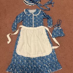 Charming blue floral prairie dress with matching bonnet and  purse  pouch. Includes a removable white apron for authentic play. Fits about 10 to 11 ye