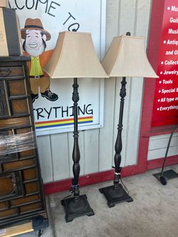 Pair of dark bronze floor lamps feature traditional turned pedestals and beige square hardback shades.