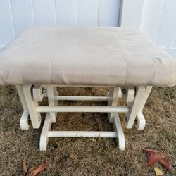 glider rocking ottoman with a white wood frame and a beige cushion