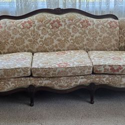 vintage sofa, often described as a 1950s floral couch or a 1970s "grandma" sofa, featuring a Victorian-style carved mahogany wood frame. It is charact