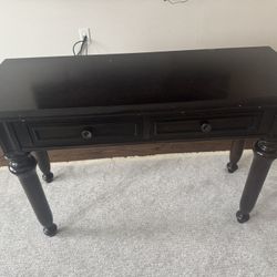 A dark wood console table featuring two drawers 