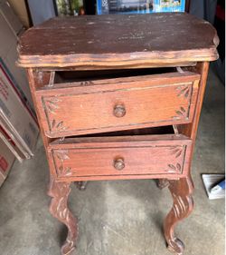 vintage two-drawer wooden side table with carved cabriole legs and floral etchings on the drawer fronts.