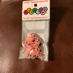 a package of small flamingo-themed Jibbitz shoe charms intended for customizing footwear like Crocs